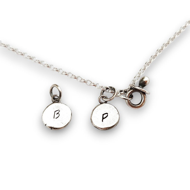 Initial silver disc pendant with baby dummy charm